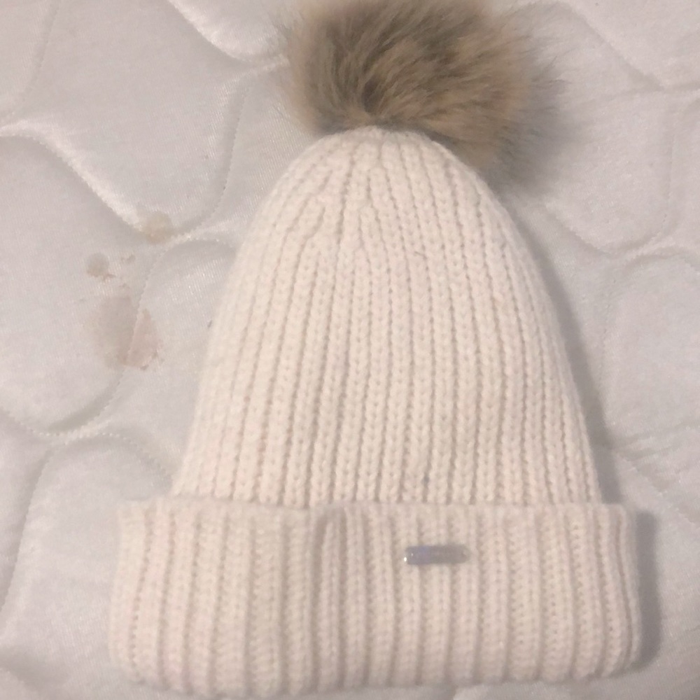 A white hat with a light drown ball on the top